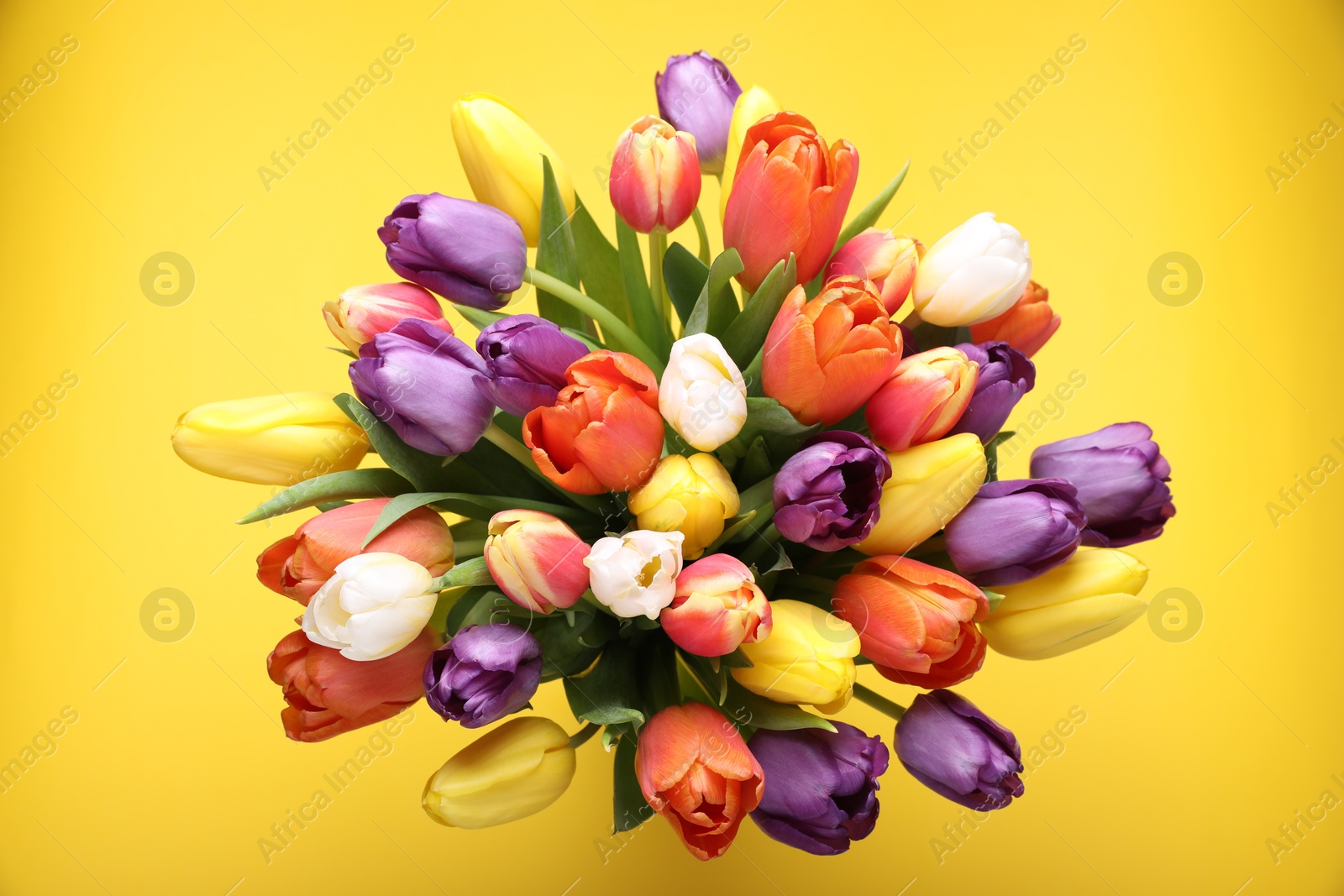 Photo of Bouquet of beautiful colorful tulips on yellow background, top view