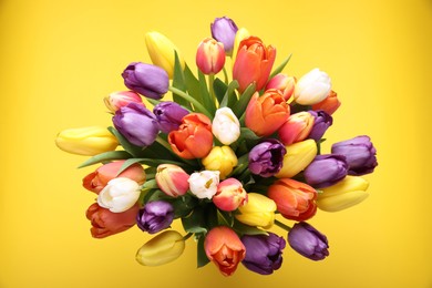 Photo of Bouquet of beautiful colorful tulips on yellow background, top view