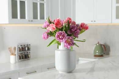 Photo of Beautiful bouquet of colorful tulip flowers on white marble table in kitchen