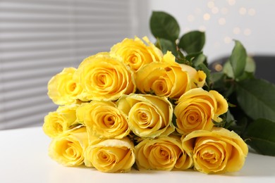 Photo of Beautiful bouquet of yellow roses on white table indoors, closeup