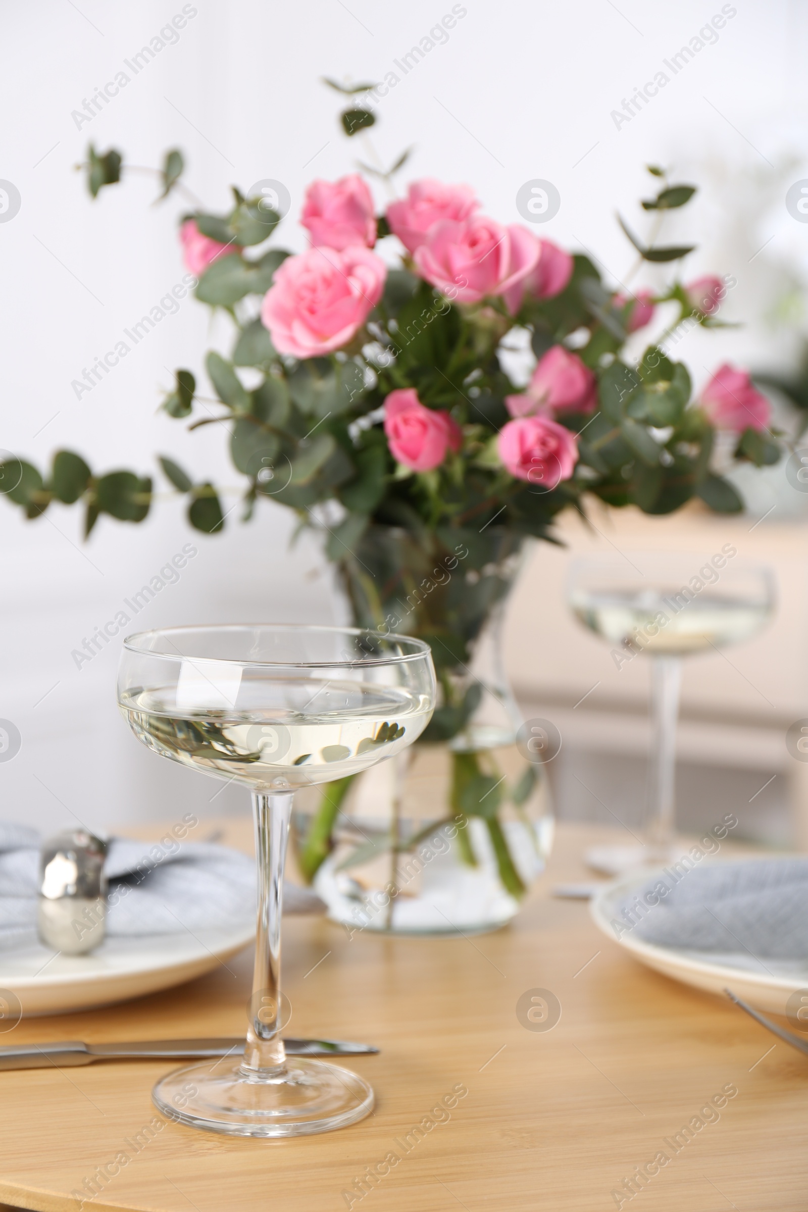 Photo of Place setting with pink roses on wooden table. Romantic dinner