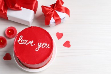 Photo of Bento cake with text Love You, gift boxes, candles and paper hearts on white wooden table, space for text. St. Valentine's day surprise