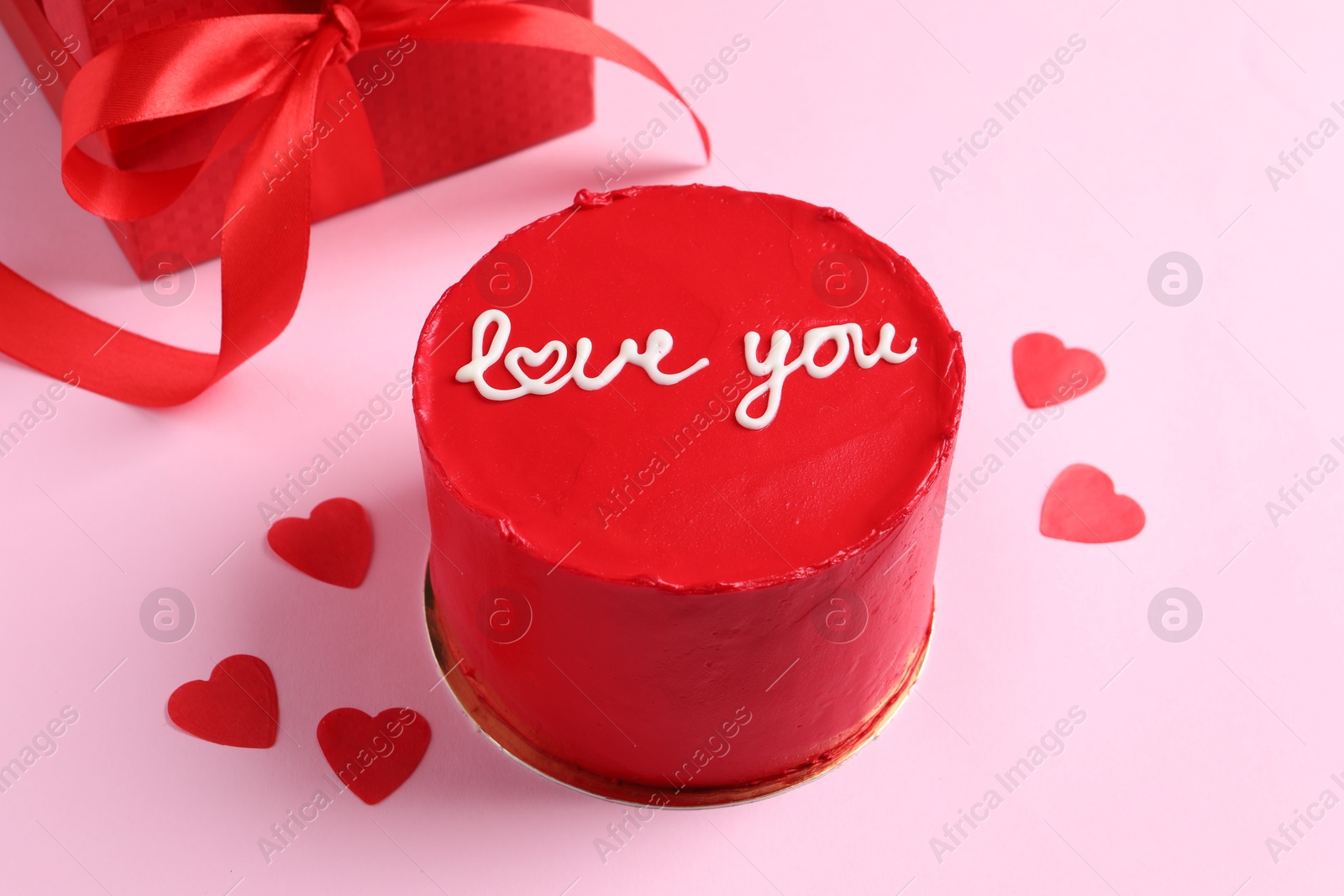 Photo of Bento cake with text Love You, gift box and paper hearts on pink table. St. Valentine's day surprise