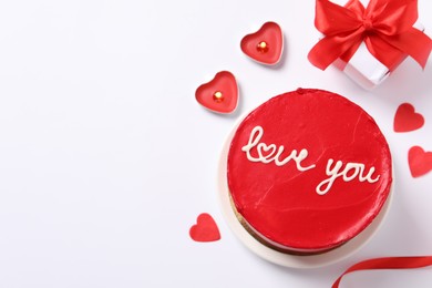 Photo of Bento cake with text Love You, candles, gift box, paper hearts and space for text on white table, flat lay. St. Valentine's day surprise