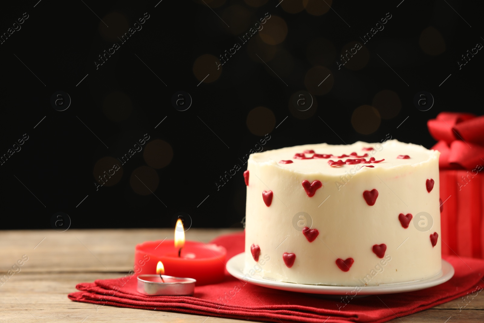 Photo of Bento cake, candles and gift box on wooden table, space for text. St. Valentine's day surprise