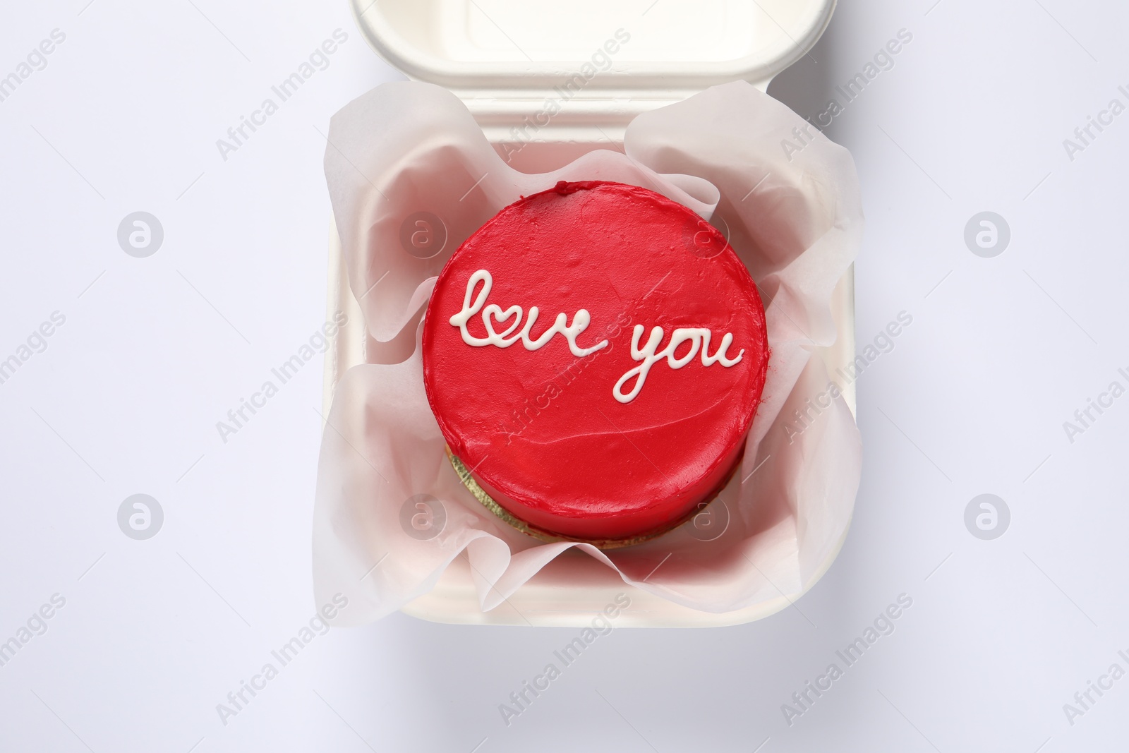 Photo of Bento cake with Love You text in takeaway box on white table, top view. St. Valentine's day surprise