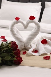 Photo of Honeymoon. Swans made of towels and beautiful red roses on bed