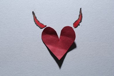 Photo of Red crumpled paper heart with horns on gray background, top view