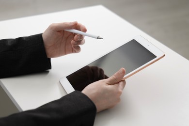 Photo of Businessman using tablet at white table indoors, closeup. Modern technology