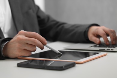 Photo of Businessman using different devices at white table indoors, closeup. Modern technology