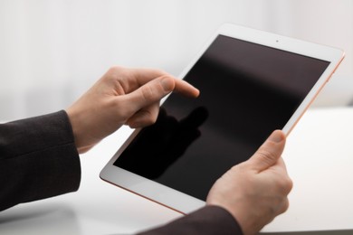 Photo of Businessman using tablet on blurred background, closeup. Modern technology