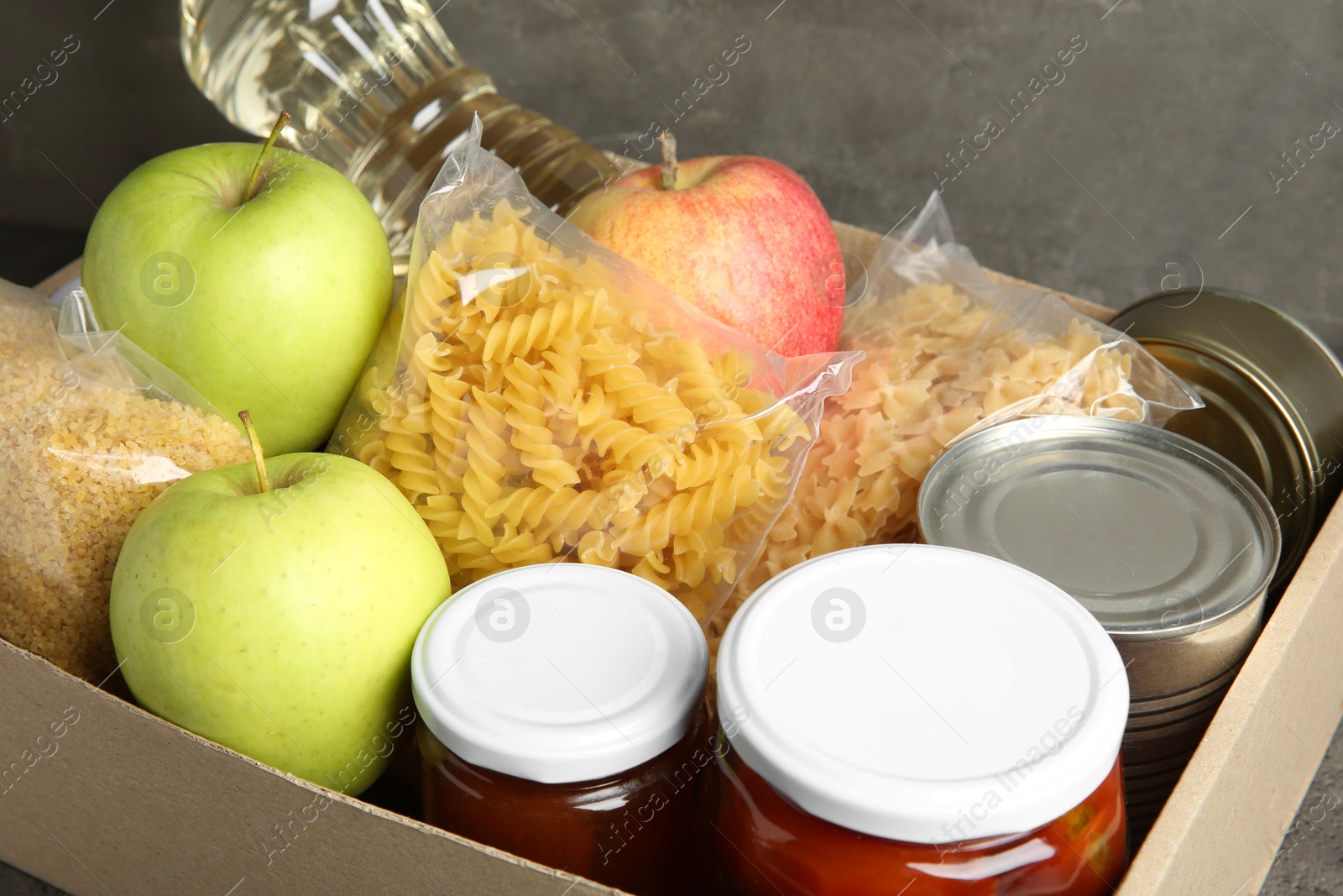 Photo of Different food products for donation in box on table, closeup