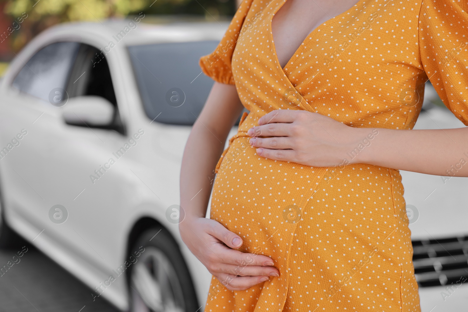 Photo of Pregnant woman near car outdoors, closeup. Space for text