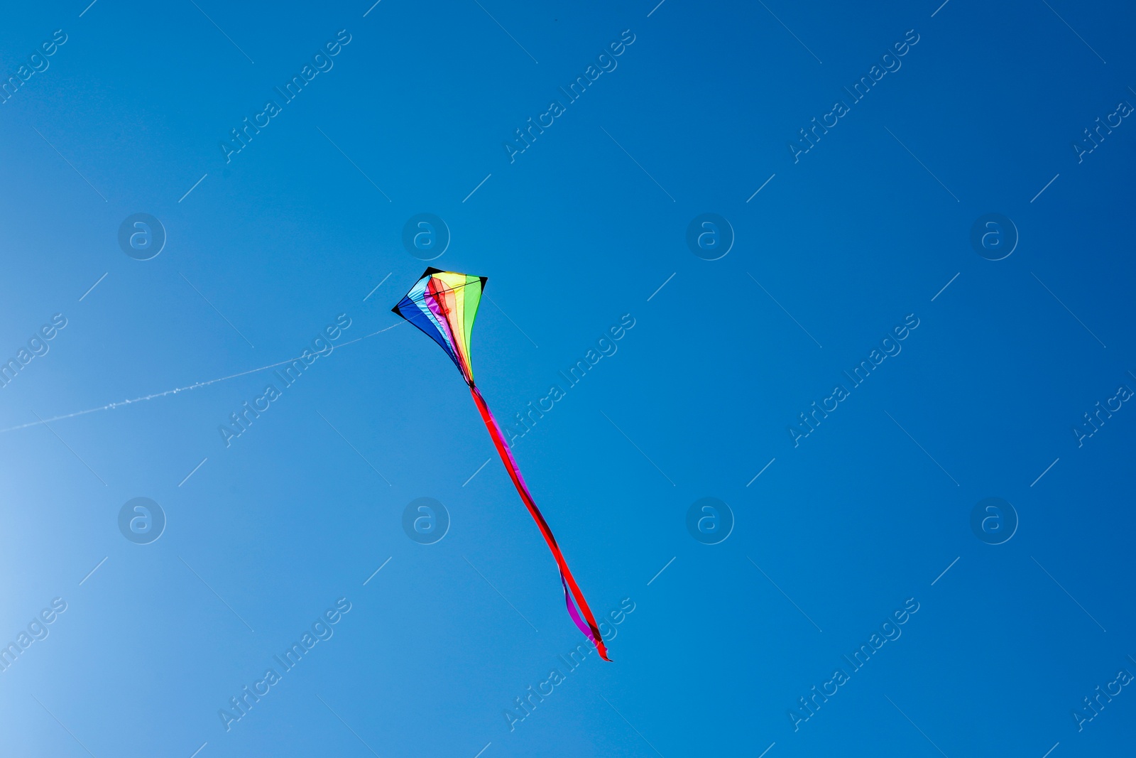 One colorful kite flying in blue sky. Space for text Photo of One colorful kite flying in blue sky. Space for text