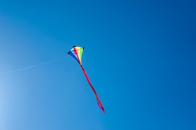Photo of One colorful kite flying in blue sky. Space for text