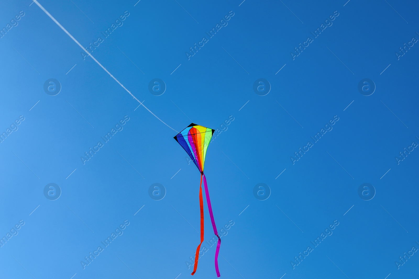 One colorful kite flying in blue sky. Space for text Photo of One colorful kite flying in blue sky. Space for text