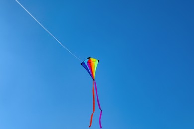 Photo of One colorful kite flying in blue sky. Space for text