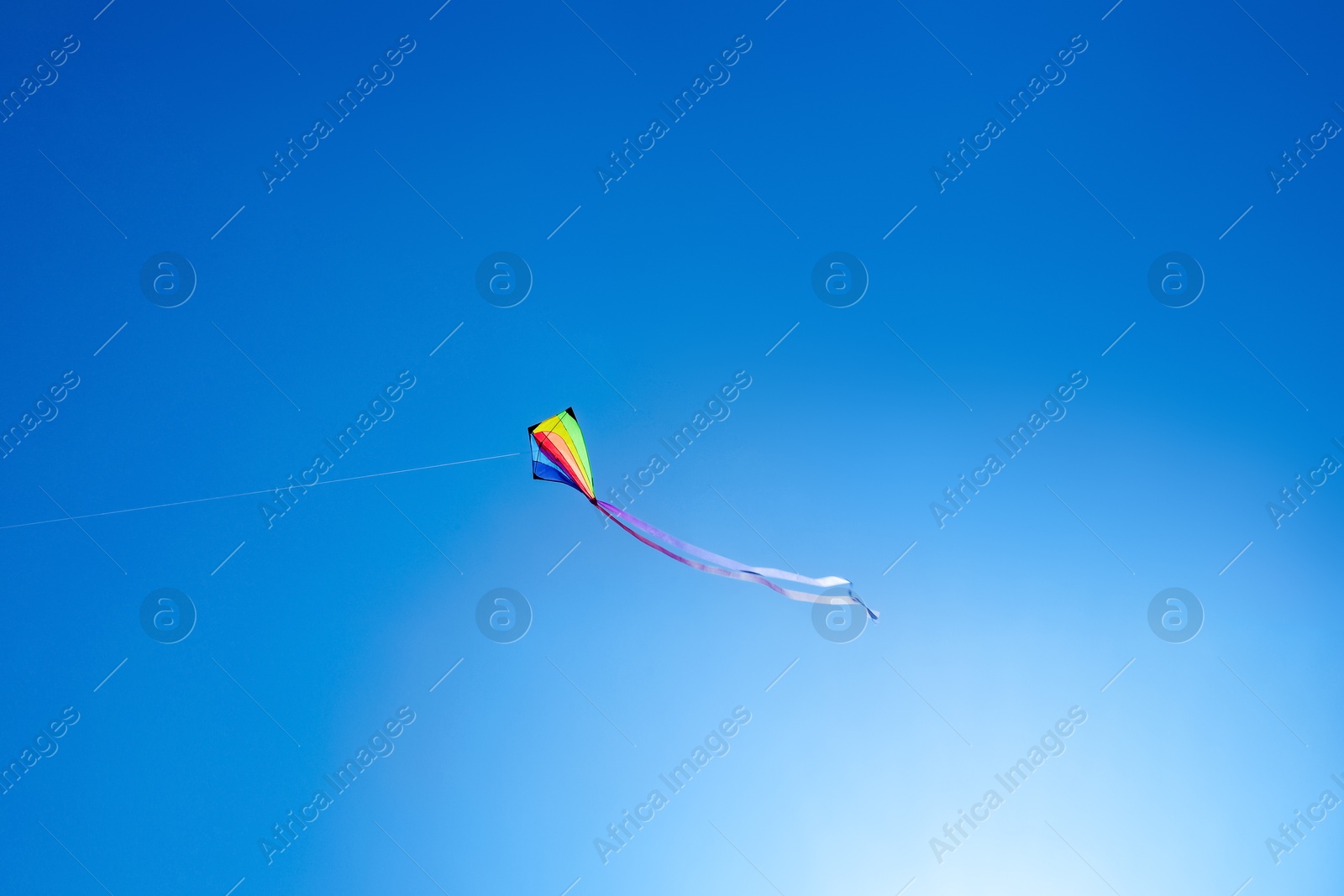 One colorful kite flying in blue sky on sunny day Photo of One colorful kite flying in blue sky on sunny day