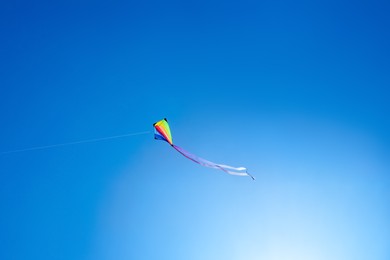 Photo of One colorful kite flying in blue sky on sunny day