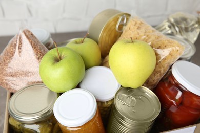 Photo of Different products in box on table, closeup. Food donation