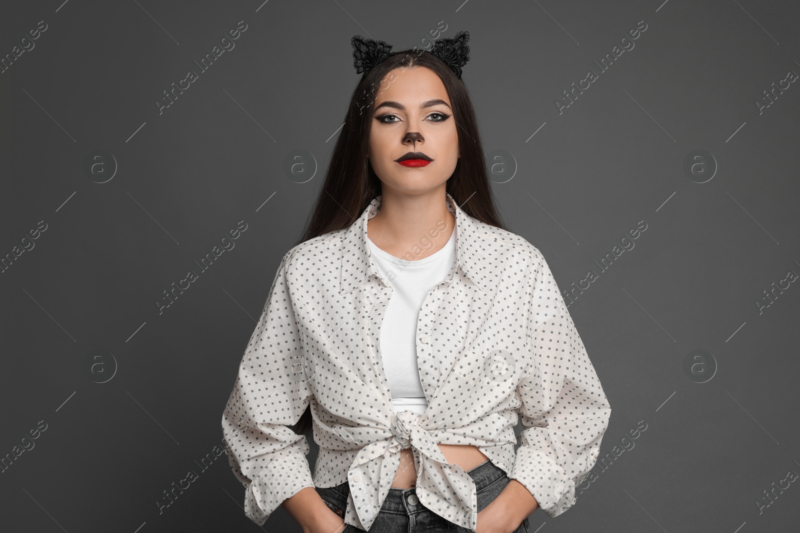 Photo of Attractive woman with cat makeup and ears on grey background