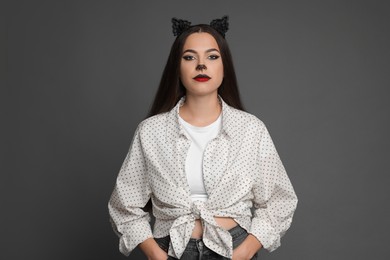 Photo of Attractive woman with cat makeup and ears on grey background