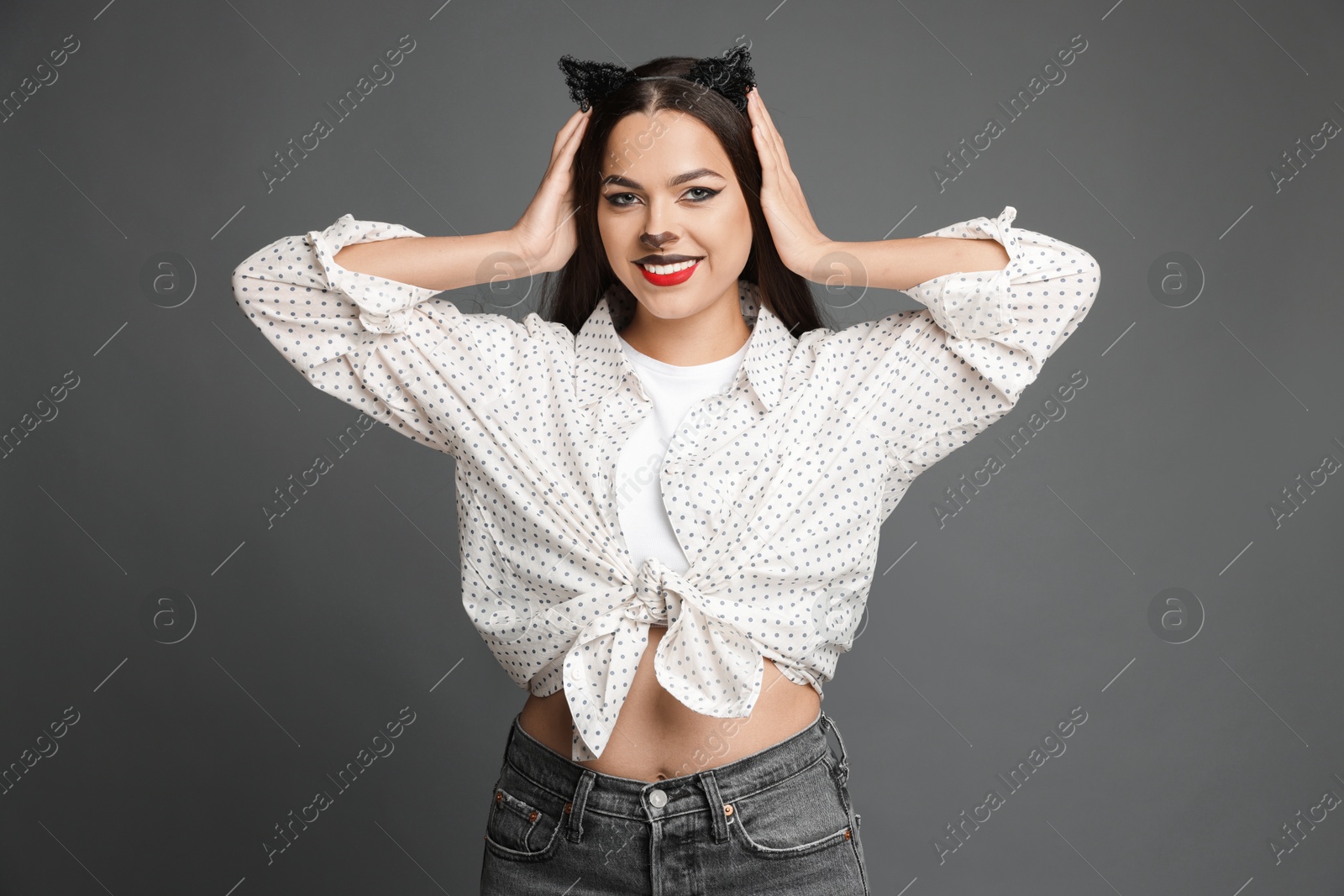 Photo of Attractive woman with cat makeup and ears on grey background