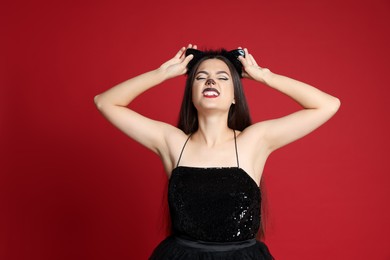 Photo of Beautiful woman with cat makeup and ears on red background