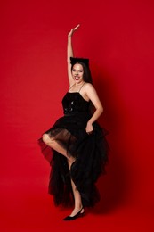 Woman with cat makeup and ears in beautiful dress on red background