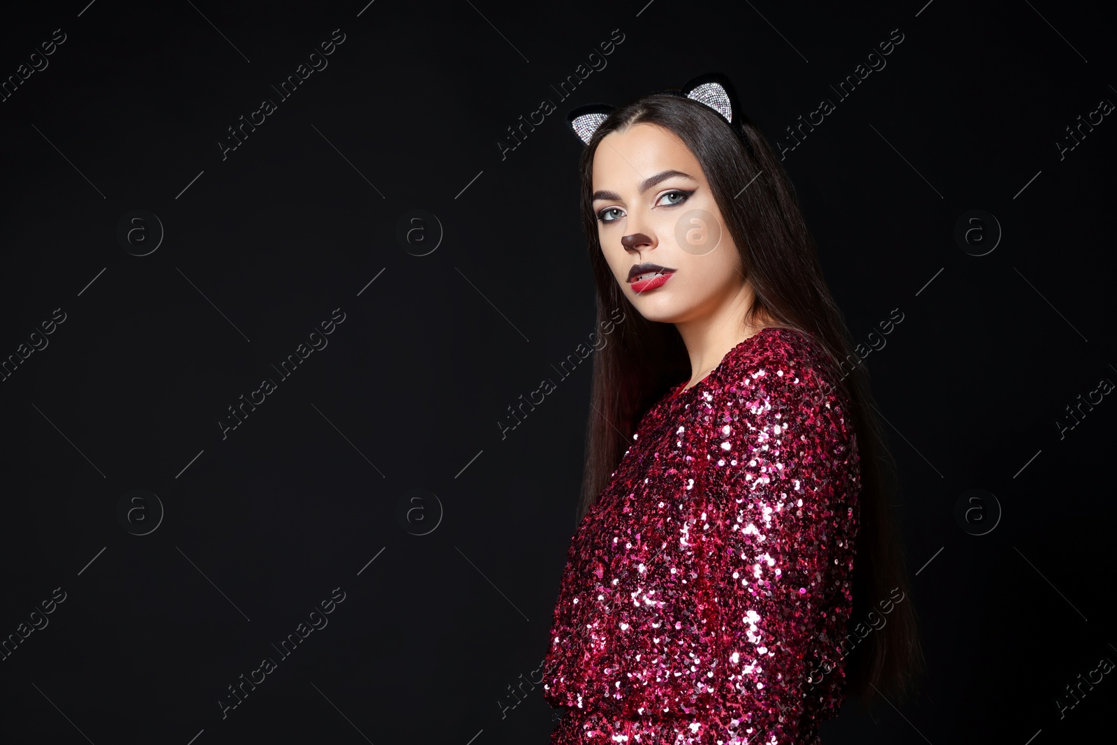 Photo of Charming woman with cat makeup and ears on black background. Space for text