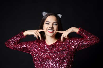 Photo of Charming woman with cat makeup and ears on black background