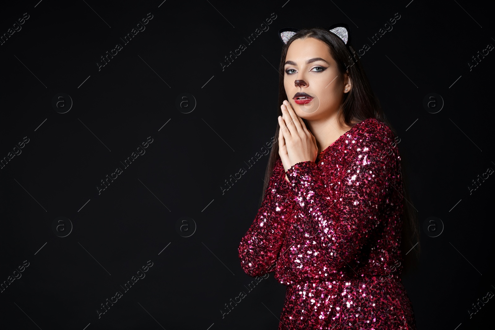 Photo of Charming woman with cat makeup and ears on black background. Space for text