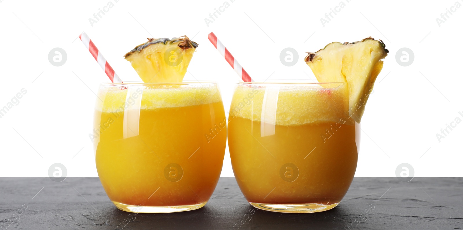 Photo of Tasty pineapple cocktail in glasses on black table against white background