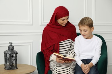 Muslim woman and her son reading Quran at home