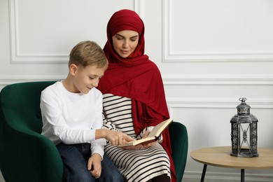 Photo of Muslim woman and her son reading Quran at home