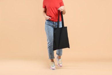 Photo of Woman with blank black shopper bag on color background, closeup. Mockup for design