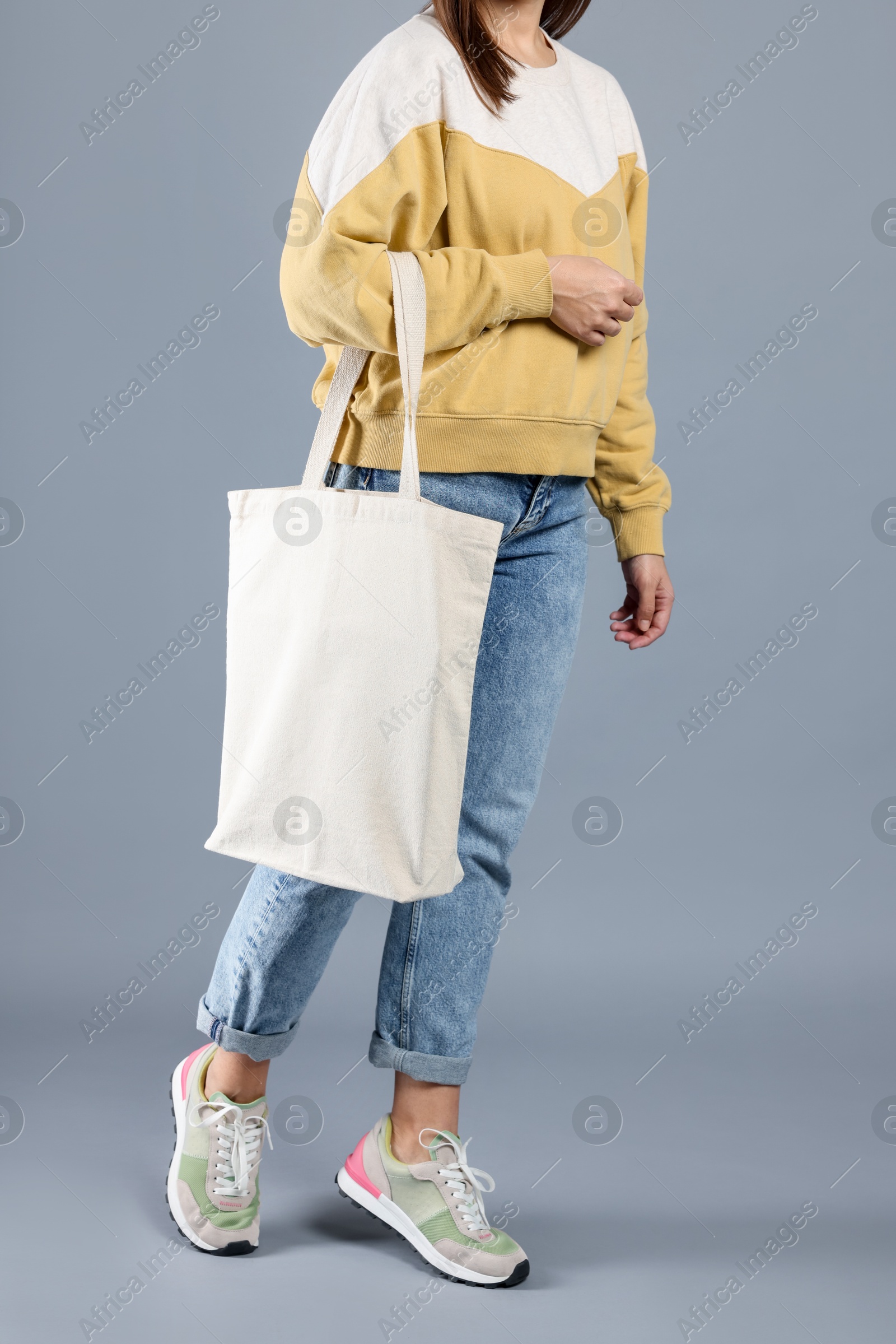 Photo of Woman with blank shopper bag on grey background, closeup. Mockup for design