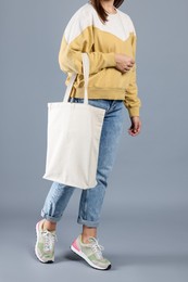 Photo of Woman with blank shopper bag on grey background, closeup. Mockup for design