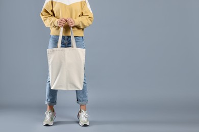 Photo of Woman with blank shopper bag on grey background, closeup. Mockup for design