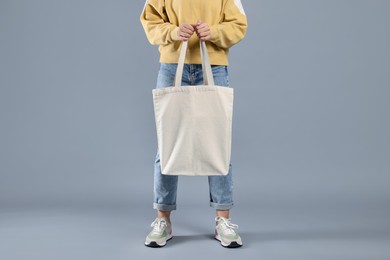 Photo of Woman with blank shopper bag on grey background, closeup. Mockup for design