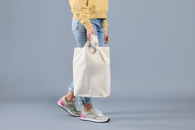 Photo of Woman with blank shopper bag on grey background, closeup. Mockup for design