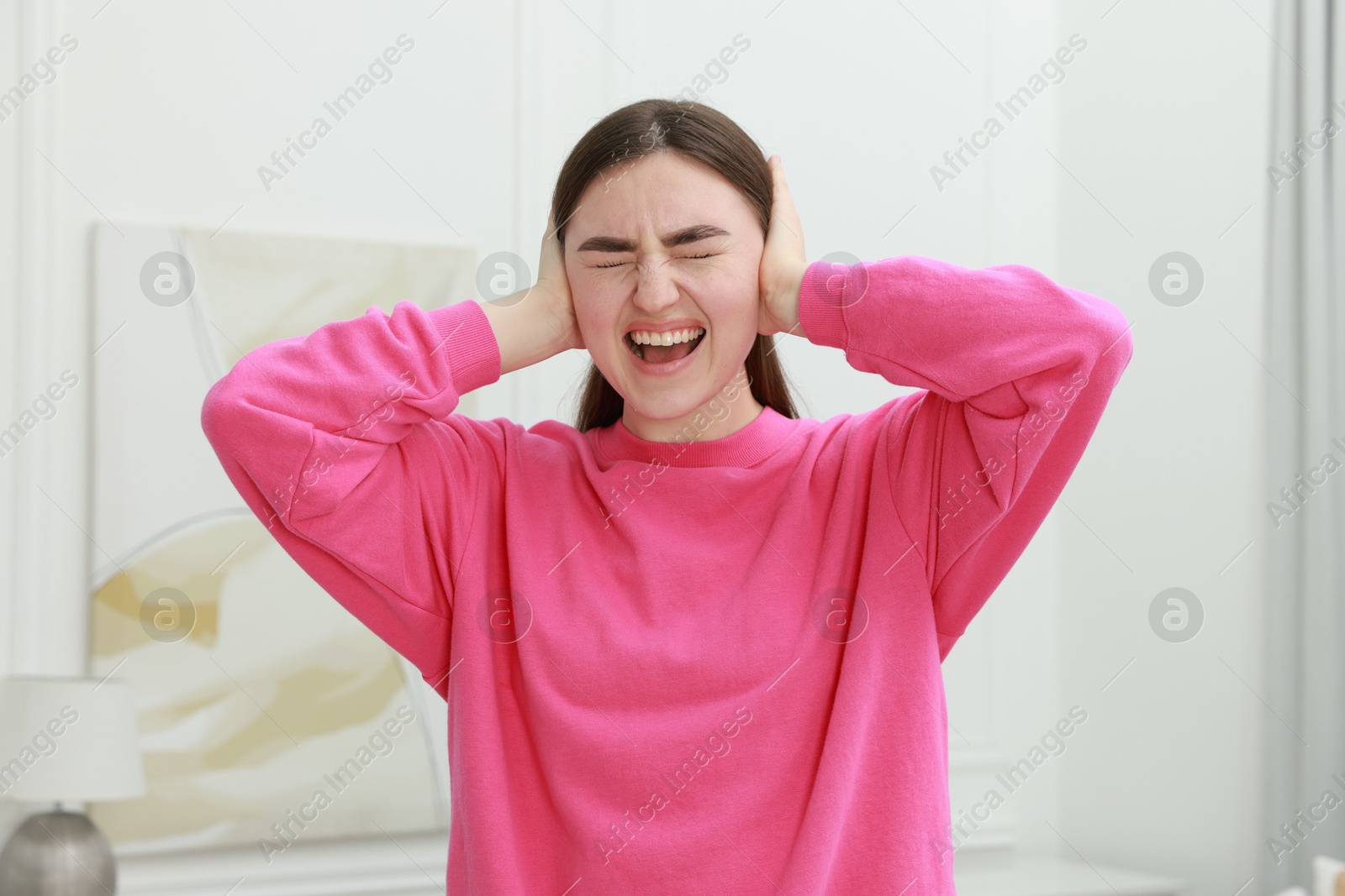 Photo of Frustrated woman covering her ears from loud noise at home