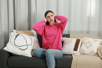 Photo of Annoyed woman covering her ears from loud noise at home