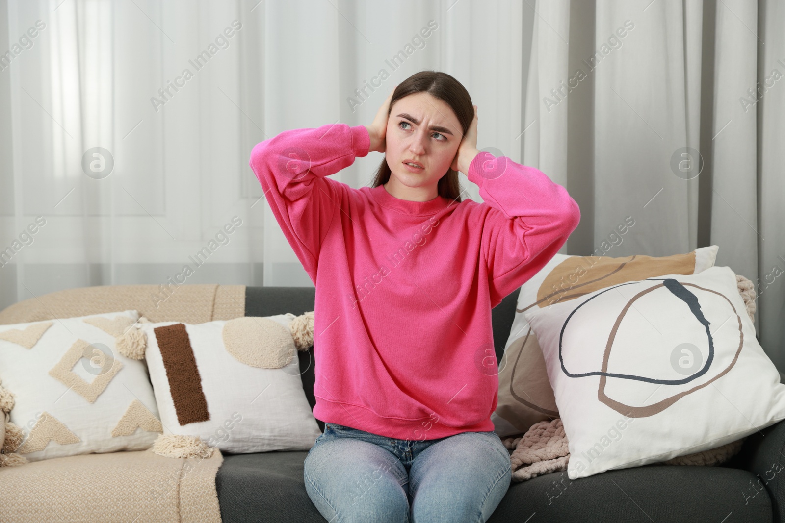 Photo of Annoyed woman covering her ears from loud noise at home