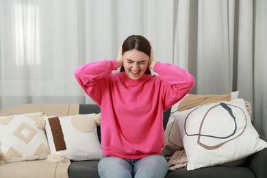 Photo of Frustrated woman covering her ears from loud noise at home