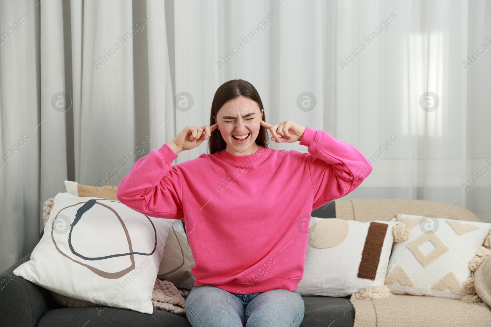 Photo of Frustrated woman covering her ears from loud noise at home