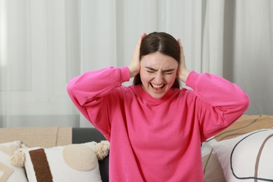 Photo of Frustrated woman covering her ears from loud noise at home