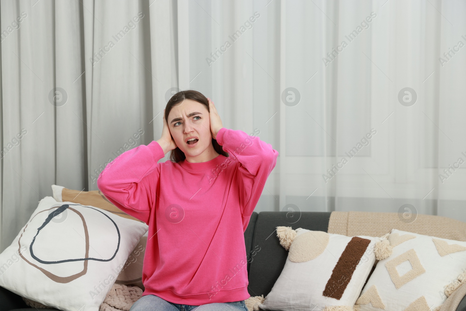 Photo of Frustrated woman covering her ears from loud noise at home