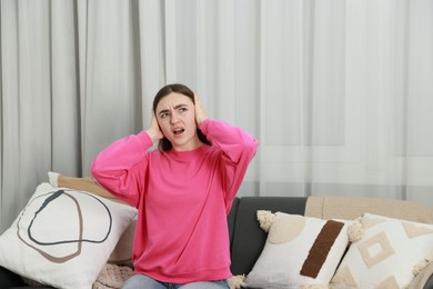 Photo of Frustrated woman covering her ears from loud noise at home