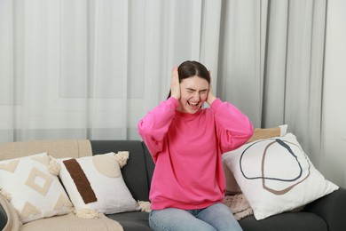 Photo of Frustrated woman covering her ears from loud noise at home